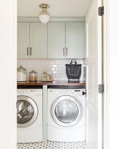 a washer and dryer in a small room next to each other with white cabinets