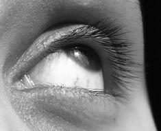 black and white photograph of an eye with long lashes looking in the opposite direction to the camera