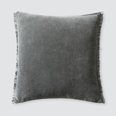 a gray pillow with fringe trim