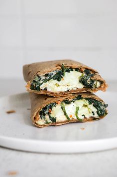 two burritos with cheese and spinach on a plate