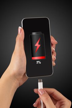 two hands holding an electronic device with a lightning symbol on the screen and charging it