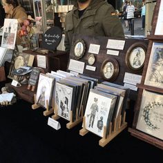 a man standing next to a display of framed pictures and other items in front of him