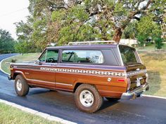 a brown truck driving down a street next to a tree