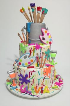 a multi - tiered cake decorated with paintbrushes and other art related items