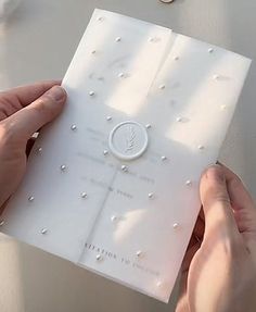 two hands are holding a card with pearls on it