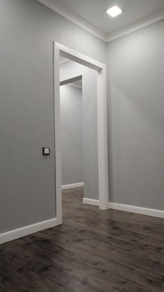 an empty room with gray walls and white trim on the doors, wood flooring