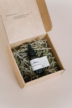 an open box with a bottle of essential oil in it sitting on top of hay