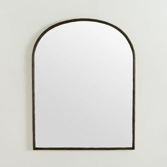 an arched mirror hanging on the wall with a black frame and metal trim around it