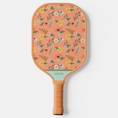 a wooden paddle with an orange floral print on the front and back, it's attached to a wall