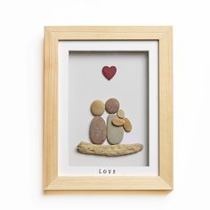 two pebbles sitting on a branch with a heart in the middle and love written below