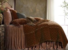 a bed with brown bedspread and pillows in a room next to a window