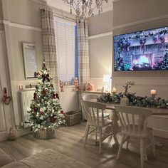 a living room with a christmas tree in the corner and a flat screen tv above it