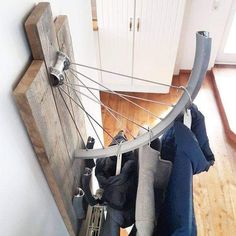 there is a bike tire hanging on the wall next to some coats and shoes in front of it