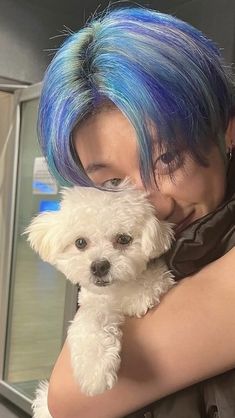 a woman with blue hair holding a white dog