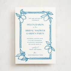 a blue and white wedding card with an ornate border on the front, featuring leaves and flowers