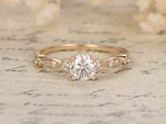 a close up view of a diamond ring on a piece of paper with flowers in the background