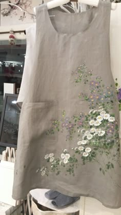 a woman's dress with flowers painted on the front and back, hanging from a rack