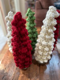 three crocheted christmas trees sitting on top of a wooden table next to a couch