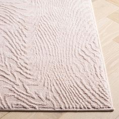 a beige rug on top of a wooden floor