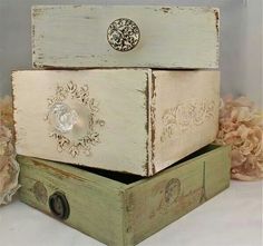 three wooden boxes stacked on top of each other with lace and flowers in the background