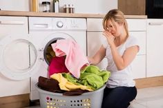 a woman sitting on the floor next to a washing machine