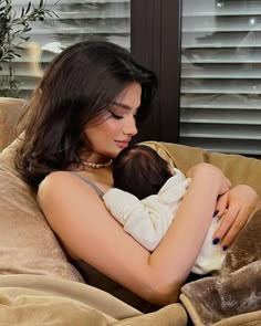 a woman holding a baby on top of a couch