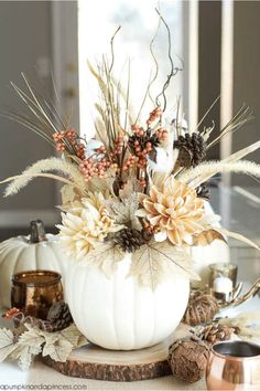 a white pumpkin decorated with dried flowers and leaves