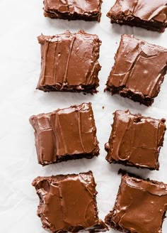 six pieces of chocolate cake sitting on top of a white tablecloth covered in frosting