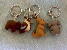 four different key chains with small stuffed animals hanging from it's sides on a blue cloth