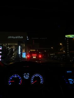 the dashboard of a car at night with its lights on