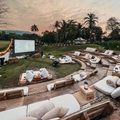 an outdoor movie is set up in the middle of a field with white couches and pillows