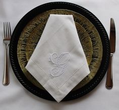 a black plate topped with a white napkin and silverware