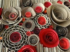 several rolled up flowers sitting on top of a bamboo tablecloth covered in red and grey paper