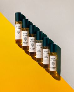 five bottles of ouda atta on top of a yellow and white wall next to each other