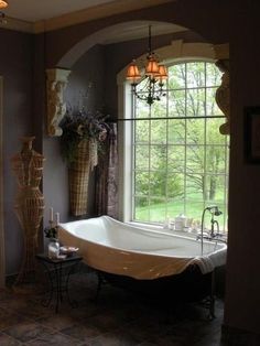 a bathtub sitting in front of a window next to a table with candles on it