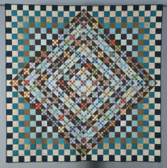 a blue and brown quilt hanging on the wall