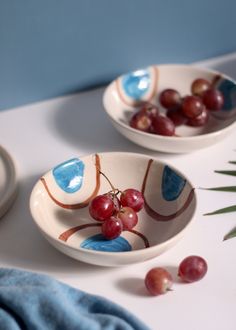 two bowls with grapes in them sitting on a table