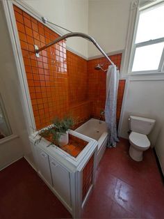 an orange tiled bathroom with a tub and toilet