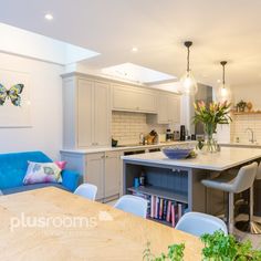 an open kitchen and dining room area in a house with white cabinets, blue couches and wooden table