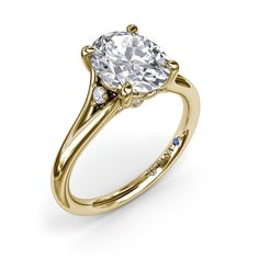 a yellow gold engagement ring with an oval cut diamond in the center and side stones