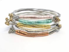 This music inspired bangle bracelet is custom made with recycled guitar strings in your size and favorite color! These are truly unique pieces of handmade jewelry that make the perfect gift for music lovers, guitar players, musicians, concertgoers and the rockstars in your life! ⚡ D E T A I L S ⚡ ✦ Guitar string bracelet wrapped in wire - choose your favorite color from 13 options! ✦ Size: Made-to-order in sizes XS-XXL. (This is a bangle bracelet and slides over the hand. Please measure the widest part of your hand around the knuckles.) XS - 7" S - 7.5" M - 7.75" L - 8 XL - 8.25" XXL - 8.75" ✦ Guitar string is flexible, but does not stretch or adjust in size. If it's not a good fit, no worries! You can exchange it for a different size within 14 days. ✦ Free Shipping: Your order ships fast Guitar Bracelet, Guitar String Jewelry, Guitar String Bracelet, String Jewelry, Beaded Jewelry Bracelets, Guitar Pics, Guitar Players, Music Jewelry, Festival Jewelry