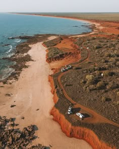 an aerial view of a beach with cars parked on the sand and water in the background