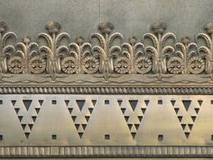 an ornate design on the side of a building with geometrical designs and leaves in gold