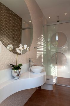 a white sink sitting under a round mirror in a bathroom