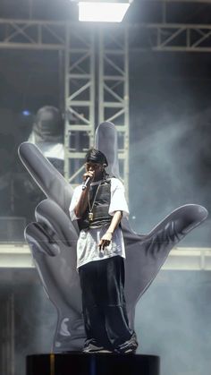 a man standing on top of a stage holding a cell phone to his ear while wearing a vest