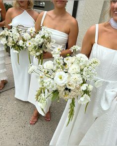 four bridesmaids in white dresses holding bouquets