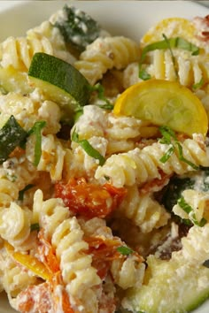 pasta salad with zucchini, tomatoes and cucumbers in a white bowl