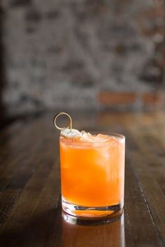 an orange drink sitting on top of a wooden table