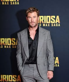 a man in a suit standing on a red carpet