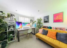 a living room filled with furniture and lots of plants on the wall next to a computer desk